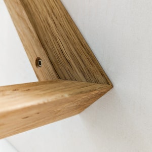 K&ouml;nnte beinhalten: Nahaufnahme eines Holzregalbrettes mit einer sichtbaren Schraube. Das Regalbrett ist aus hellbraunem Holz mit nat&uuml;rlicher Maserung.