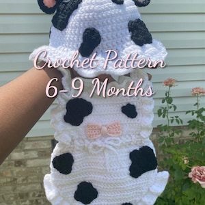 May include: A white and black crochet cow outfit for babies, featuring a hat with horns and a romper with black spots and a pink bow. The text "Crochet Pattern 6-9 Months" is visible.