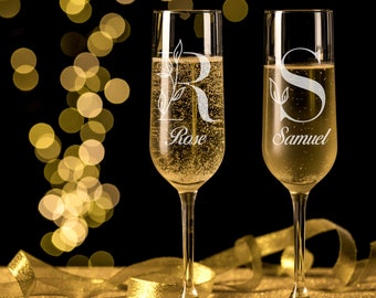 May include: Two champagne flutes with personalized engravings. The flutes are filled with champagne and have the names "Rose" and "Samuel" etched on them.