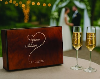 May include: A wooden box and two champagne flutes on a table. The box is dark brown with a heart design and the names "Veronica & Adrian" and the date "14.10.2025" engraved on it. The flutes have the same names and heart design.