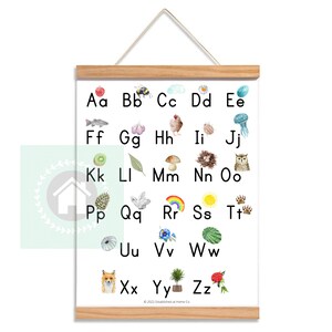 May include: A white poster with a wooden frame features the alphabet from A to Z with a watercolor illustration of an object or animal representing each letter.  The illustrations include a red apple, a bee, a cloud, a daisy, a jellyfish, a kiwi, a leaf, a mushroom, a nest, an owl, a pine cone, a dove, a rainbow, a sun, animal tracks, a seashell, a flower, a watermelon, a fox, a tree, and a rose.