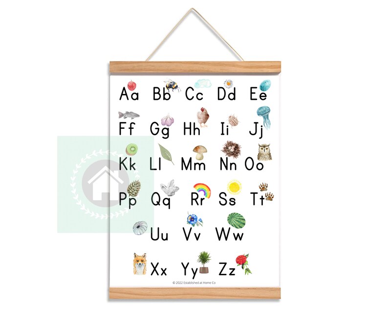 May include: A white poster with a wooden frame features the alphabet from A to Z with a watercolor illustration of an object or animal representing each letter.  The illustrations include a red apple, a bee, a cloud, a daisy, a jellyfish, a kiwi, a leaf, a mushroom, a nest, an owl, a pine cone, a dove, a rainbow, a sun, animal tracks, a seashell, a flower, a watermelon, a fox, a tree, and a rose.