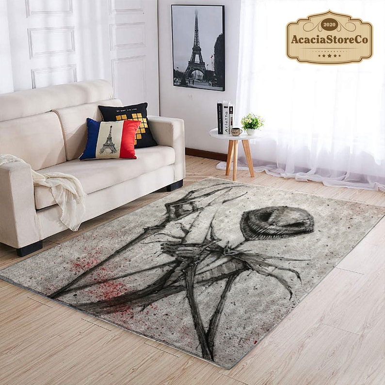 May include: A rectangular area rug with a distressed, abstract design in shades of gray and black, featuring a central, circular shape and spiky, linear elements. Red accents add a pop of color. The rug is placed on a light-colored wooden floor.