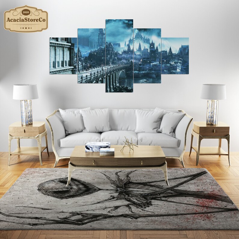 May include: A living room setup featuring a five-panel wall art depicting a fantasy city in shades of blue and gray. The room includes a white sofa, wooden side tables with lamps, a coffee table, and a patterned rug with a dark, abstract design.