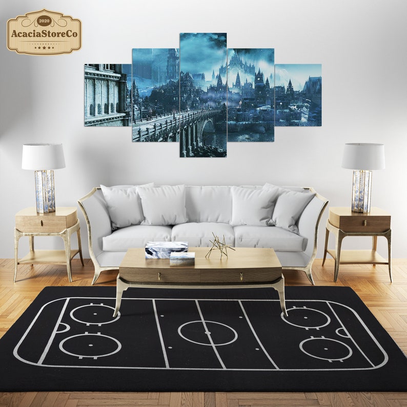 K&ouml;nnte beinhalten: Ein schwarz-wei&szlig;er Hockeyfeld-Teppich mit drei Kreisen in der Mitte. Der Teppich liegt auf einem Holzboden vor einem wei&szlig;en Sofa und zwei Beistelltischen mit Lampen.