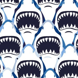 May include: A seamless pattern featuring a repeating design of white shark jaws with rows of sharp teeth, set against a blue and white background.