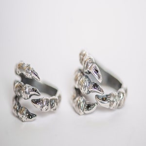 May include: Two silver rings shaped like a claw with black gemstones on each claw.