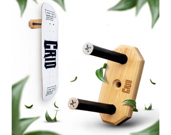 May include: A wooden skateboard wall mount with two black metal arms. The mount is made of light brown wood and has the word "GRID" engraved on it. The mount is designed to hold two skateboards.