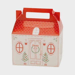 May include: A festive, house-shaped gift box with a red brick-patterned roof and a white facade. The facade features a door with a wreath, windows, and Christmas tree illustrations. The box has a handle for easy carrying.