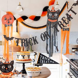 Halloween-themed decorations including a cat, pumpkin, and the 'Trick or Treat' banner with two bats on each end on a kitchen wall.
