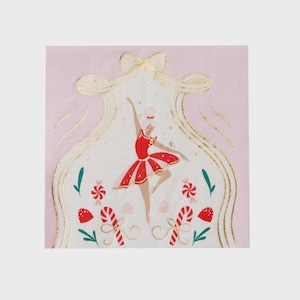 May include: A pink paper napkin with a gold-outlined design featuring a ballerina in a red dress. The design includes candy canes, snowflakes, and a bow. The ballerina is in a dancing pose.