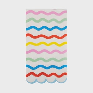Puede incluir: Una servilleta de papel rectangular con fondo blanco y líneas onduladas de colores rosa, verde, azul, rojo, amarillo y rosa. El borde inferior tiene un diseño festoneado.