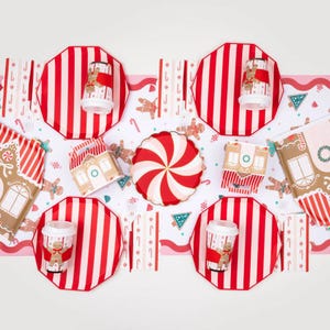 Gingerbread-themed holiday table setup with striped plates and candy décor.
