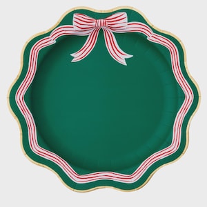 May include: A green paper plate with a scalloped edge and a gold trim. The plate is decorated with a red and white striped ribbon design around the edge and a bow at the top. Festive party supplies.