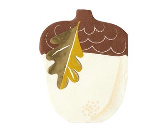 May include: A white paper napkin with a brown and gold acorn design. The acorn has a brown cap and a gold leaf.