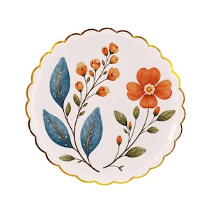 May include: A round paper plate with a scalloped edge and a metallic gold rim. The center features a white background decorated with a botanical illustration of blue leaves with gold accents and orange flowers on thin brown stems.