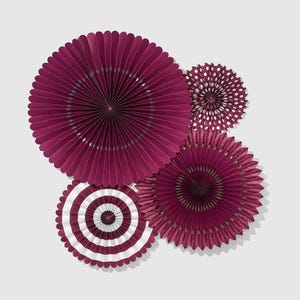 May include: An overhead shot of four decorative paper fans in varying sizes. The largest fans are a deep burgundy color, while the smaller ones feature white polka dots and stripes. These paper fans are ideal for party decorations.