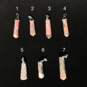 May include: Seven pink and grey gemstone pendants with silver bail. The pendants are numbered 1 through 7.