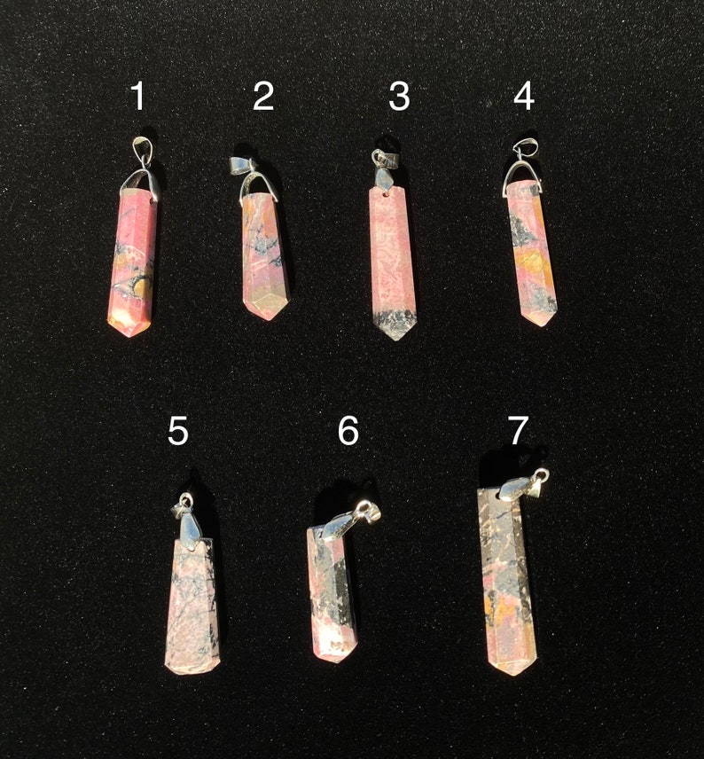 May include: Seven pink and grey gemstone pendants with silver bail. The pendants are numbered 1 through 7.
