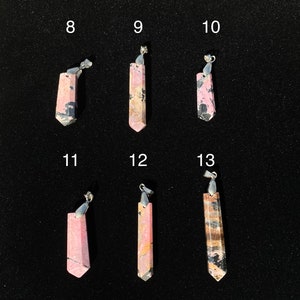 May include: Six pink and black gemstone pendants with silver bail. The pendants are numbered 8 through 13.