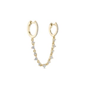 May include: A pair of gold hoop earrings with a dangling chain of small diamonds.
