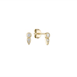 May include: A pair of gold earrings with small, clear gemstones. Each earring features a round gemstone at the top and a smaller, pointed gemstone below it.