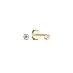 May include: A pair of gold stud earrings with a small, clear diamond in the center of each earring.