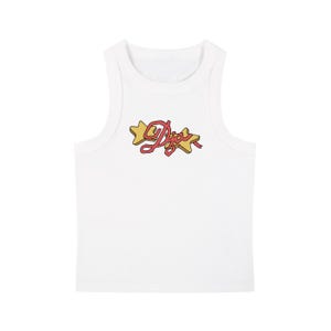 Op de afbeelding: Witte geribbelde tanktop met een grafisch ontwerp. Het ontwerp toont het woord "Dior" in een cursief lettertype, met een roze lint en twee gele sterren.