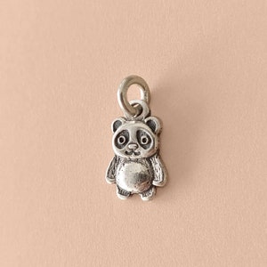 Op de afbeelding: Een zilveren bedel in de vorm van een pandabeer. De bedel heeft een lus aan de bovenkant om aan een armband of ketting te bevestigen.
