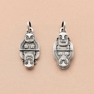 Peut inclure: Deux pendentifs en argent en forme de visage stylisé avec des motifs géométriques. Les pendentifs sont détaillés avec des reliefs et ont une finition texturée.