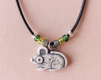 May include: A black cord necklace with green, yellow, and silver beads and a silver mouse charm.