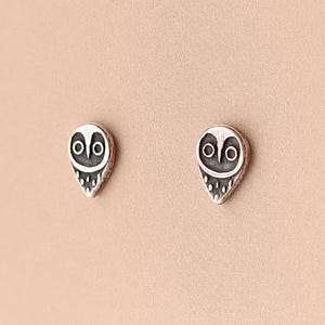 May include: A pair of silver owl stud earrings. The owls are detailed with black eyes and a white body.