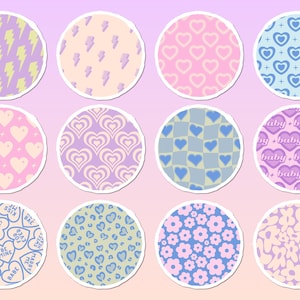 May include: A set of twelve circular stickers featuring various patterns including yellow lightning bolts, pink hearts, blue hearts, checkered prints, the word baby, conversation hearts with text, leopard spots, and floral designs.
