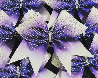 May include: Purple and white cheer bows with silver glitter and rhinestones. The bows have a gradient effect from white to purple.