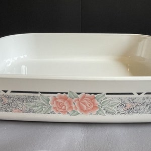 Könnte beinhalten: Weißes rechteckiges Backgeschirr mit Griffen. Das Geschirr hat ein dekoratives Band mit rosa Rosen, grauen und schwarzen Akzenten. Ideal zum Backen und Servieren.