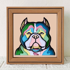 May include: A framed, colorful, paper-cut art piece of a dog's face. The dog has a green, blue, pink, and yellow color scheme.