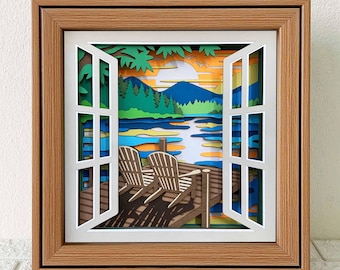 May include: A framed paper art piece depicting a serene lake scene viewed through an open window. The artwork features two chairs on a wooden dock, with a colorful landscape of mountains, trees, and water. The frame is a warm brown color.