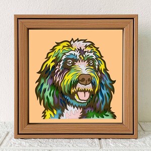 May include: A colourful paper cut-out of a dog's head in a wooden frame. The dog has a white muzzle, brown eyes, and a pink tongue. The paper cut-out is layered with different colours, including green, blue, yellow, and pink.