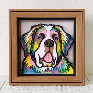 May include: A colorful paper cut-out of a Saint Bernard dog's head in a wooden frame. The dog's fur is layered with shades of pink, yellow, green, and blue.