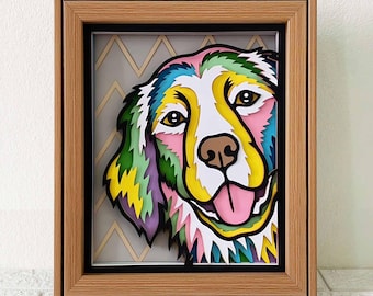 Puede incluir: Una obra de arte de papel en capas y colorida de la cara de un perro en un marco de madera. El pelaje del perro se representa en tonos de verde, amarillo, rosa y azul. El fondo es un patrón de chevron gris y blanco.