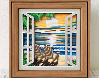 May include: A framed paper art piece showing a beach scene through an open window. The artwork features a sunset over the sea, two beach chairs, and palm trees. The frame is made of light brown wood.