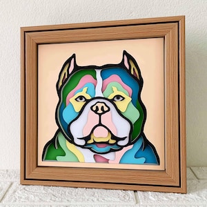 May include: A framed, colorful, paper-cut art piece of a dog's face. The dog has a green, blue, pink, and yellow patterned face.