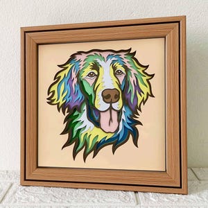Puede incluir: Una obra de arte de papel en capas multicolores enmarcada de la cabeza de un perro. El perro tiene una cara blanca con la lengua rosa que sobresale, y su pelaje está en capas de tonos verdes, azules, amarillos y morados.