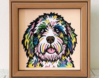 Puede incluir: Una obra de arte en papel enmarcada de la cara de un perro. El perro es de raza blanca y esponjosa, con la lengua rosa y la nariz negra. El pelo del perro está en capas de tonos verdes, azules, amarillos y rosas.