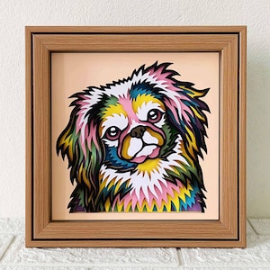 May include: A colorful paper cut-out of a Pekingese dog in a wooden frame. The dog's fur is layered in shades of pink, yellow, green, and blue.