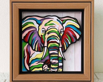 May include: A colorful, layered paper art piece of an elephant in a wooden frame. The elephant is depicted with vibrant hues of red, yellow, green, purple, and blue. The artwork is a unique, eye-catching piece of home decor.
