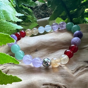 May include: A multi-colored beaded bracelet with a silver charm. The bracelet features beads in shades of red, orange, yellow, green, blue, purple, and white.