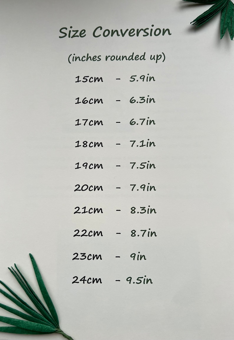 May include: A white paper with the text "Size Conversion" and a list of centimeter to inch conversions. Measurements range from 15cm (5.9in) to 24cm (9.5in). Green decorative leaves are in the corners.