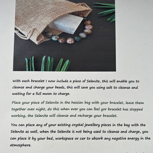 May include: A bracelet with multi-colored beads and a Selenite crystal, presented with a small burlap bag. The bracelet is displayed on a dark surface with green accents. The image also includes text about cleansing and charging the beads.