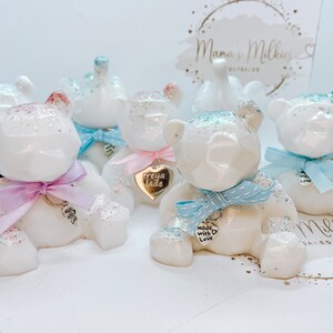 Op de afbeelding: Vijf witte keramische teddyberen met glitteraccenten. Elke beer heeft een zilveren charmeketting met een hartvormig label. De labels hebben verschillende inscripties, waaronder "Made with Love" en "Freya Jade".